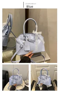 Detail of light blue shell bag with lace bow and adjustable shoulder strap