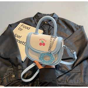 Vue détaillée du sac selle bleu et blanc avec imprimé cerise et pendentif donut