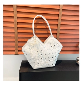 Close-up of white tote bag with black bow embroidery and lace pearl pendant detail