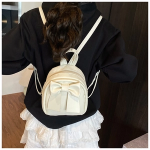 Close-up of cream-colored mini bow backpack with smooth PU leather finish and zipper detail