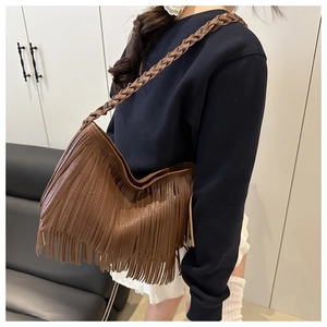 Détail d'un sac à bandoulière en cuir marron avec de longues franges et une sangle tissée