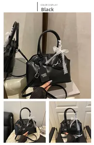 Detail of black matte leather handbag featuring white lace bow and long shoulder strap