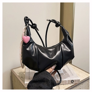 Détail du sac croissant plissé noir avec logo fashion, breloque cœur et foulard noué
