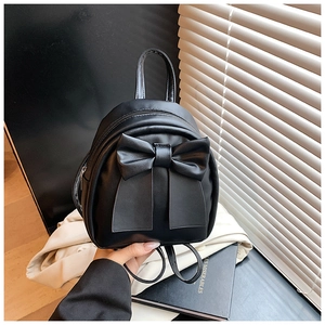 Mini black backpack featuring a prominent bow design and versatile top handle