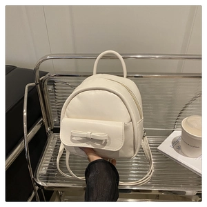 Detail of white PU leather mini backpack with bow decoration on a display shelf