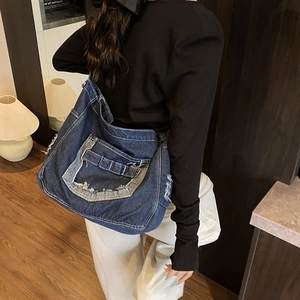 Grande borsa tote in denim blu scuro con dettagli vintage indossata da una modella