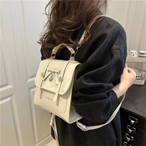 Creamy white mini college style backpack with bow and heart pendant on model
