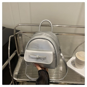Close-up of stylish silver mini backpack with ribbon detail on a modern metal display