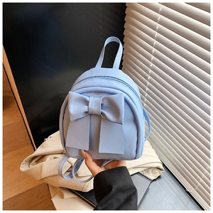 Close-up of a light blue mini backpack with large bow detail and premium PU leather texture