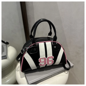 Détail d'un sac bowling en cuir noir et blanc avec un écusson rose du chiffre 96