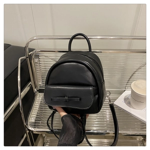 Detail of black synthetic leather mini backpack with a delicate bow and silver hardware