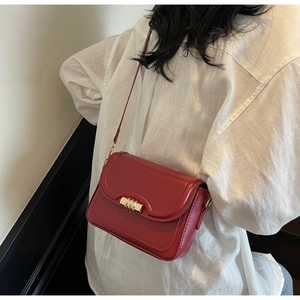 Detail of vintage burgundy leather square bag with golden buckle on white shirt