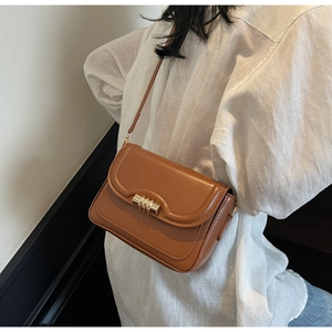Detail of caramel leather crossbody bag featuring gold metal twist-lock and slim strap