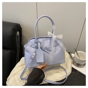 Detail view of light blue handbag with white lace bow and chic hanging tag on silk cloth