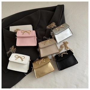 Flat lay of mini crossbody bags in six colors with gold bow buckles and chain straps