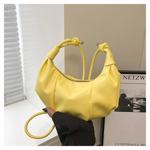 Détail d'un sac demi-lune jaune avec bandoulière nouée et texte fashion embossé
