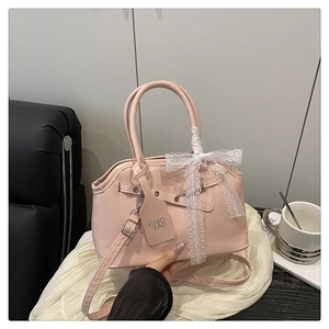 Detail of pink crossbody bag featuring white lace bow and adjustable leather strap