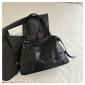 Détail du grand sac cabas noir en simili cuir avec coutures en X et boucles métalliques