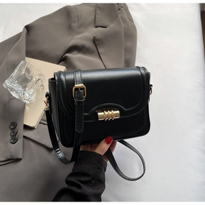 Close-up of black leather square bag with a golden cylindrical twist lock and shoulder strap