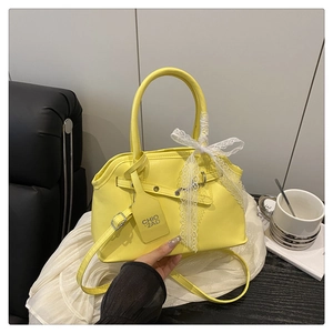 Detail of a bright yellow square handbag with lace bow and metal buckle strap adjustment