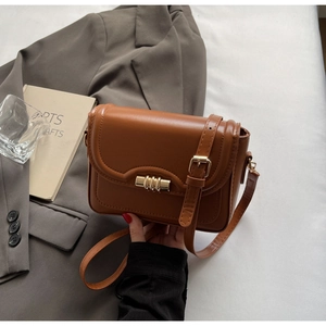 Close-up of caramel brown glossy PU leather bag featuring a gold cylindrical lock detail