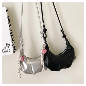 Détail du sac croissant argenté avec bandoulière nouée et pendentif coeur rose