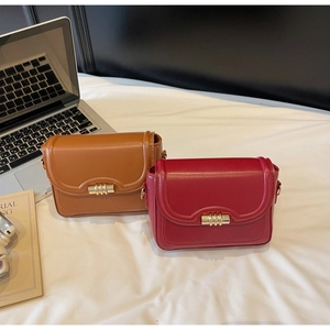 Detail showing red and brown vintage faux leather crossbody bags with golden cylinder locks