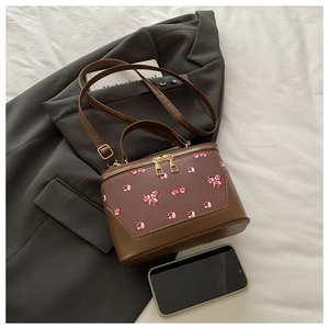 Detail view of cylinder box bag with cherry print and golden double zippers on a blazer