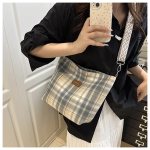 Detail of checkered canvas bag with wide geometric pattern strap and leather patch