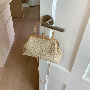 Detail of gold woven chain bag with vintage bead handle hanging on a white door