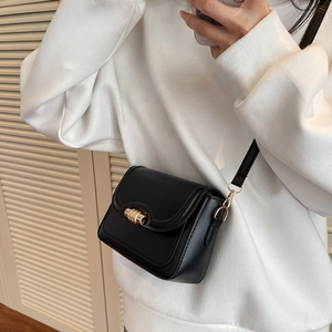 Classic black leather crossbody bag with gold metal buckle shown on a model