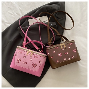 Detail of pink and brown cherry print box bags with dual gold zippers and handles