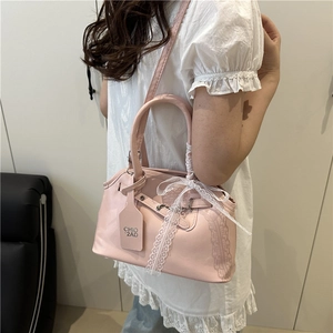 Pink matte leather handbag with white lace bow decoration and adjustable shoulder strap