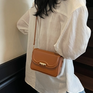 Vintage brown crossbody bag with gold buckle shown on shoulder for a stylish casual look