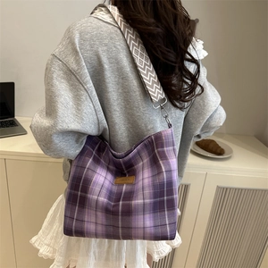 Purple plaid tote bag with wide woven strap shown in a modern interior setting