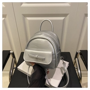 Close-up of mini silver backpack with bow detail on a stylish black metal chair