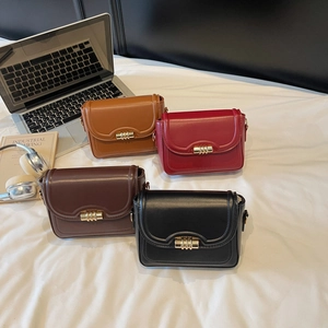 Minimalist vintage crossbody bags in four colors with cylindrical gold locks on a bed