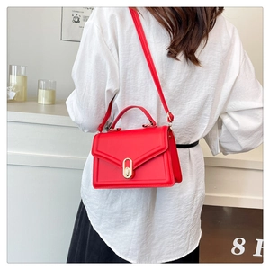Détail d'un sac bandoulière rouge avec fermoir doré et bandoulière réglable en cuir