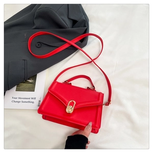 Vue détaillée du fermoir en métal doré élégant sur un sac à bandoulière rouge chic