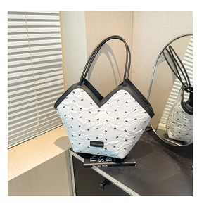 Close-up of a white tote bag with black bow prints and a unique V-shaped opening design