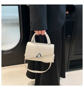 Close-up of cream beige crossbody bag with herringbone texture and silver heart buckle