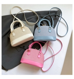 Detailed view of woven shell-shaped handbags in beige, blue, and pink with leather base