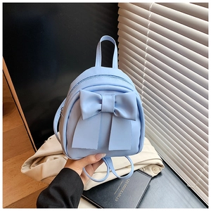 Close-up of light blue mini backpack with decorative bow and textured PU leather