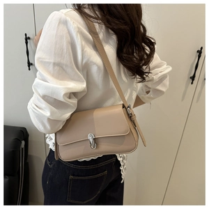 Detailed side view of beige minimalist shoulder bag with silver buckle worn under the arm