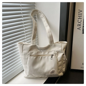 Close-up of white canvas tote bag with zipper pocket and lucky logo detail