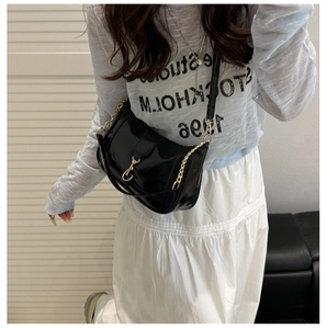 Chic black crescent saddle bag with gold buckle on a model wearing a floral top