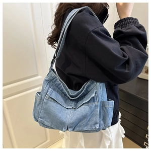 Lifestyle view of light blue denim crossbody bag with pockets and adjustable strap
