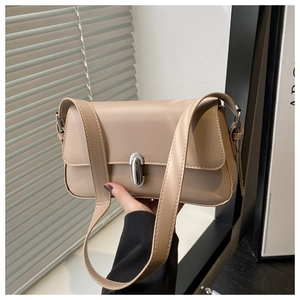 Close-up of minimalist beige shoulder bag with silver capsule metal buckle and smooth leather