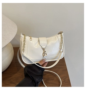 Detail of white minimalist crescent bag with golden chain and clasp in cozy setting