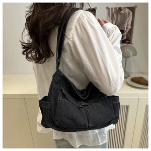 Model wearing a black denim utility crossbody bag with multiple pockets in a minimalist setting